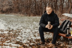 Winter Serenity: 40-Year-Old Man Enjoying Tea On Snow-Covered Bench In Rural Park. Immerse Yourself In The Tranquil Beauty Of Winter As A 40-year-old Man Finds Solace On A Snowy Bench In A Rural Park.