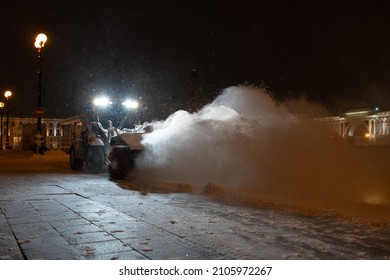 Winter Service Vehicle Clearing Thoroughfares Of Ice And Snow, Yellow Snow Plow Tractor Working On Empty Street At Night In Heavy Snowfall To Keep Roads Clear And Safe For Driving During Winter