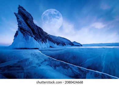 Winter Siberian landscape. Ogoy Island on Lake Baikal. Transparent patterned ice surface and mighty rock in moonlight.