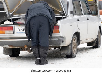 Winter Sketch. A Man In Warm Clothes Leaned Over The Open Trunk Of An Old Rusty Car. He's Going Fishing.