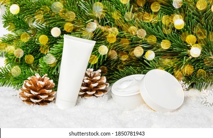 Winter Skin Care Cosmetic Products In Snow Under Christmas Tree With Pine Cones And Bokeh Lights. Face Cream Jar And Hand Creme Or Body Lotion Tube. Holiday Gift And Seasonal Skin Protection