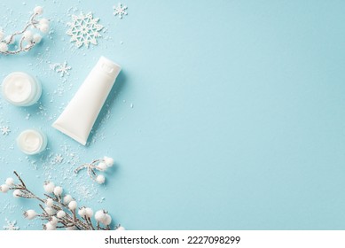 Winter skin care cosmetics concept. Top view photo of jars of cream white tube of lotion without label snowflakes sow and plant branches in frost on isolated light blue background with empty space - Shutterstock ID 2227098299
