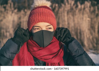 Winter smog bad air pollution Asian woman wearing mask to breathe outside cold air.