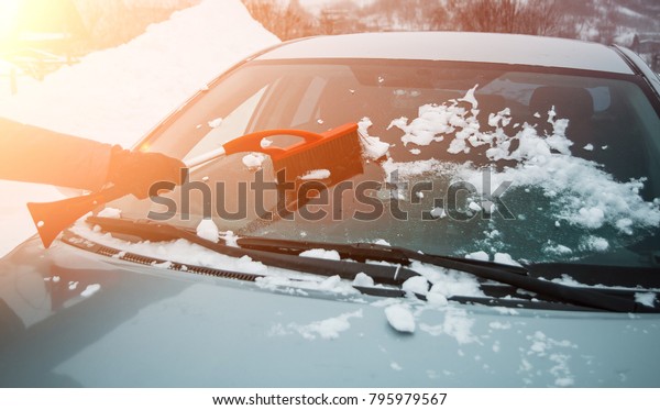 Winter, snow, car. A person\
removes the car from the snow with the help of special brushes.\
silver car