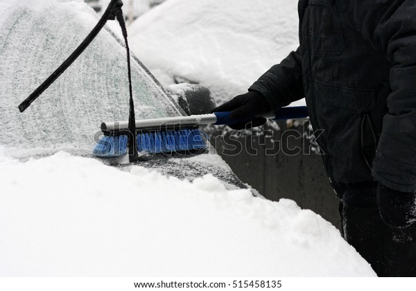 Winter, snow, car winter problems. Visible hand\
of a man in a black jacket and glove, which cleans the car from\
snow with the help of special\
brushes.