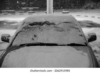 Winter Snow Cover On The Frozen Car Windshield That Raise Up The Wiper From Window In Winter Night. Car Windshield Covered With Ice And Snow