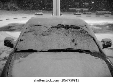 Winter Snow Cover On The Frozen Car Windshield That Raise Up The Wiper From Window In Winter Night. Car Windshield Covered With Ice And Snow