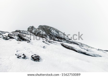 Winter snow covered mountain rock close up view.