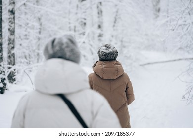 Winter snow walk woman walking away in snowy forest on woods trail outdoor lifestyle active people. Outside leisure.