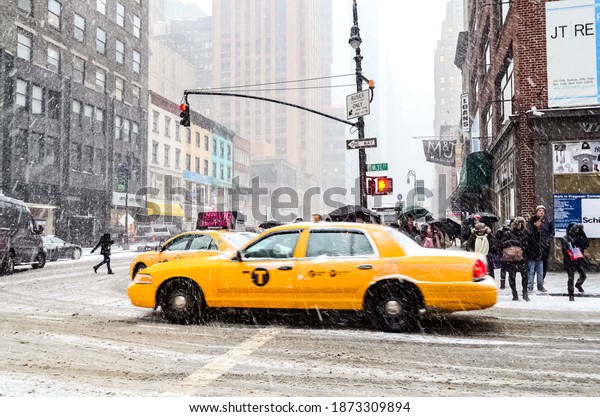 Winter snowstorm blizzard\
in New York City with heavy snow falling, cars covered in snow and\
people commuting during snow storm. Manhattan, New York, USA\
January 26, 2015.