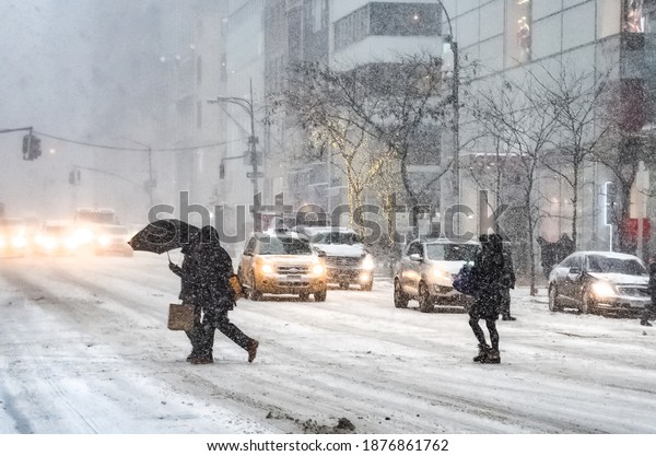 Winter snowstorm blizzard\
in New York City with heavy snow falling, cars covered in snow and\
people commuting during snow storm. Manhattan, New York, USA\
January 26, 2015.