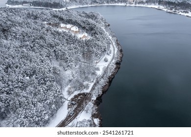 winter snowy landscape. riverbank with country road and houses in snow-covered forest. aerial view. - Powered by Shutterstock