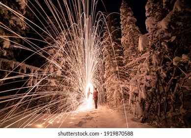 A Winter Snowy Tree, Forest, Woods Landscape With Amazing Sparking, Steel Wool Effect Shooting Sparks Across The Frozen Landscape At Night. Unique Background, Wallpaper Abstract View. 