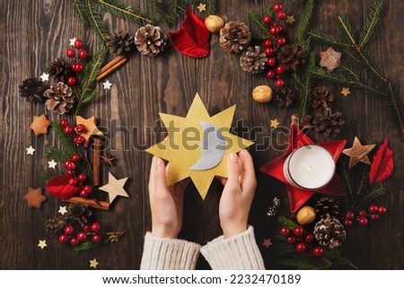 Winter solstice day, December 21. Longest night in the year concept. Sun and moon symbol in womans hands, Christmas trees, pine cones, branches with berries, candle on wooden background, top view.