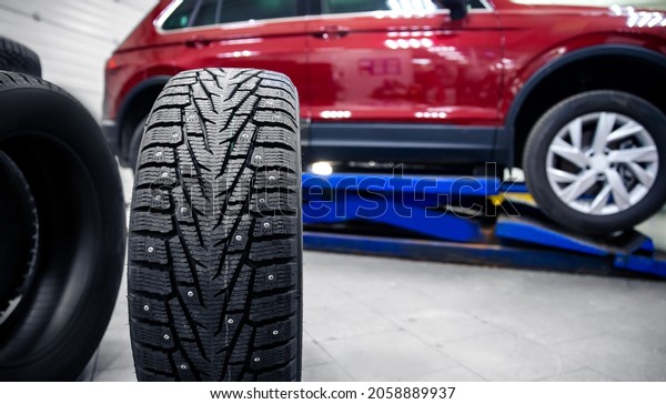 Winter spikes wheels tires replacement\
disc, car is lifted on lift in workshop\
banner.