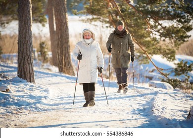 Winter Sport In Finland - Nordic Walking. Senior Woman And Man Hiking In Cold Forest. Active People Outdoors. Scenic Peaceful Finnish Landscape.