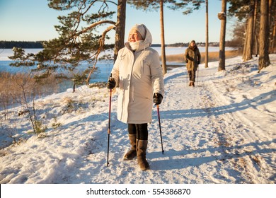 Winter Sport In Finland - Nordic Walking. Senior Woman And Man Hiking In Cold Forest. Active People Outdoors. Scenic Peaceful Finnish Landscape.