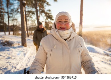 Winter Sport In Finland - Nordic Walking. Senior Woman And Man Hiking In Cold Forest. Active People Outdoors. Scenic Peaceful Finnish Landscape.