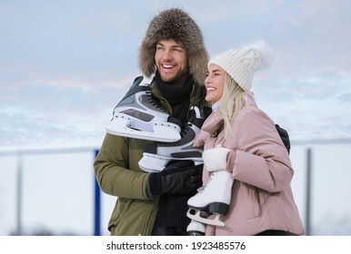 Winter Sports and Lifestyle. Young Caucasian Couple in Winter With Ice Skates Posing Together Over a Snowy Winter Landscape Outdoor. Vertical image Composition - Shutterstock ID 1923485576