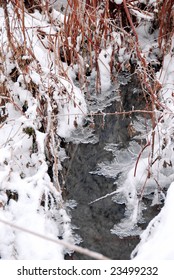 winter stream flowing through snow and ice
