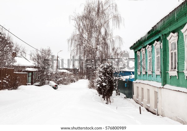 Winter street in ancient Russian\
city after snowfall. Cloudy day. Old house with icicles in the\
foreground.  City of Kolomna (Moscow region), January\
2017
