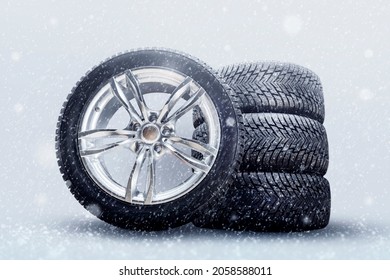 winter studded tires, a set of friction winter wheels with aluminum alloy wheels on a white background. falling snow is a safety concept about seasonal tire change for safety on the road in icy - Shutterstock ID 2058588011
