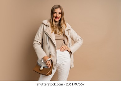 Winter Studio Fashion Photo Of Elegant Blond Woman With Red Lips Wearing Trendy Eco Leather Jacket , Posing Over Beige Background. 