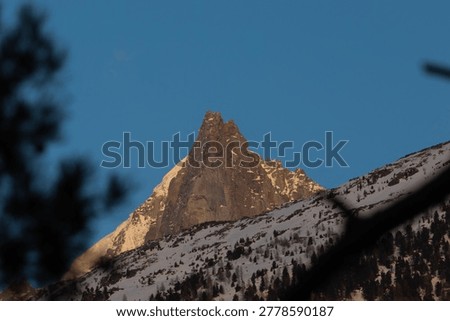 A winter summit glows softly at twilight in the cool evening atmosphere of the French Alps.