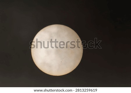 winter sun behind thick clouds, with sunspots