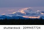 A winter sun sets over the Cascade Mountain Range in Central Oregon as viewed from Sisters Oregon just outside Bend Oregon in Central Oregon.