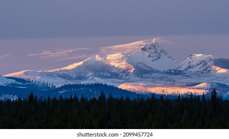 A winter sun sets over the Cascade Mountain Range in Central Oregon as viewed from Sisters Oregon just outside Bend Oregon in Central Oregon.