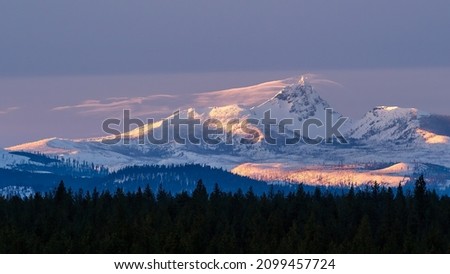 A winter sun sets over the Cascade Mountain Range in Central Oregon as viewed from Sisters Oregon just outside Bend Oregon in Central Oregon.