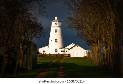 Winter sunlight falls on East Bank Lighthouse famous for The Snow Goose, against a stormy sky in Sutton Bridge, River Nene, Spalding, Lincolnshire