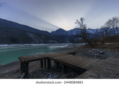 Winter sunset behind a mountain peak of a winter alpine landscape with wooden pier at reservoir lake at Barcis, Friuli-Venezia Giulia, Italy - Powered by Shutterstock