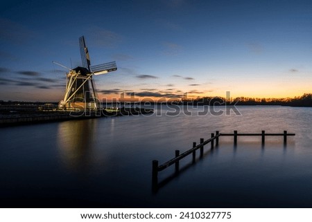 Winter sunset landscape with Dutch windmill 'De Helper' along the Paterswoldsemeer in the rural province of Groningen, The Netherlands.