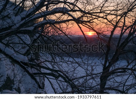 Winter sunset over the frozen river Ufa on the background of the cliff
