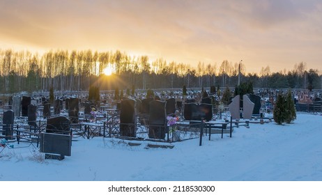 Winter sunset over a snow covered cemetery with dark headstones and trees. Afterlife. Samsara concepts. Hope for the resurrection of the dead. Space for text.
