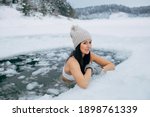 Winter swimming. Woman in frozen lake ice hole. Swimmers wellness in icy water. How to swim in cold water. Beautiful young female smiling. Gray hat and gloves swimming clothes. Nature lake in forest