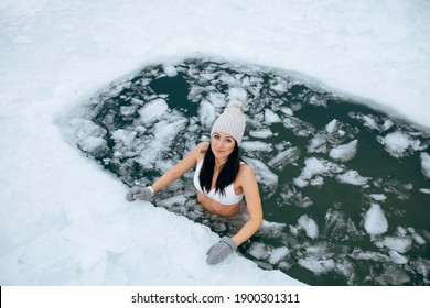 Winter Swimming. Woman In Frozen Lake Ice Hole. Swimmers Wellness In Icy Water. How To Swim In Cold Water. Beautiful Young Female Smiling. Gray Hat And Gloves Swimming Clothes. Nature Lake In Forest