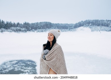 Winter Swimming. Woman Ready To Swim In Ice Water. How To Swim In Cold Water. Beautiful Young Woman Wrapped In A Towel And Swimming Clothes. Gray Hat And Gloves. People And Nature Lake In The Forest.