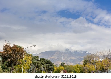 Winter Tehran Street View In Tehran International Exhibition Center With Snow Covered Alborz Mountains Against Cloudy Sky On Background