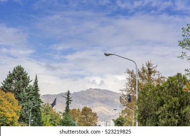 Winter Tehran Street View In Tehran International Exhibition Center With Snow Covered Alborz Mountains Against Cloudy Sky On Background