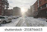 In winter, there is snow on the streets and trees and roofs. The sidewalks and roadways have not yet been cleared by public utilities. Only footprints in the snow. The sun breaks through the clouds