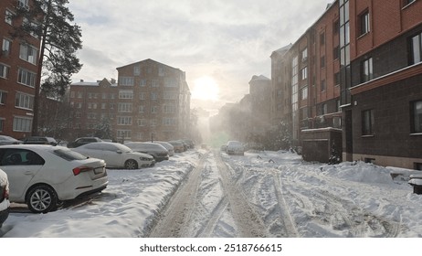 In winter, there is snow on the streets and trees and roofs. The sidewalks and roadways have not yet been cleared by public utilities. Only footprints in the snow. The sun breaks through the clouds - Powered by Shutterstock