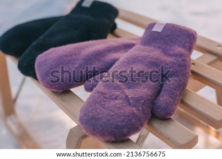 Winter time, the concept of winter and snow. Multicolored mittens on a sled. Selective focus.