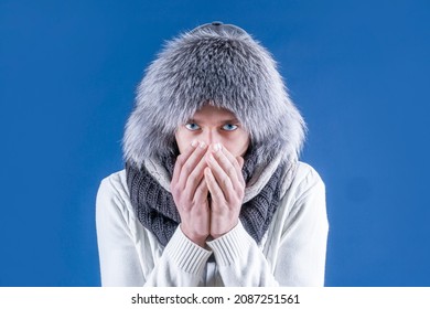 It's Winter Time. Isolate. Cold Weather. A Man In A Fur Hat And Scarf Warms His Hands With His Mouth. Bask.