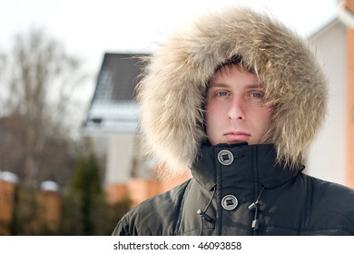 Winter time - man in warm jacket with furry hood in the yard