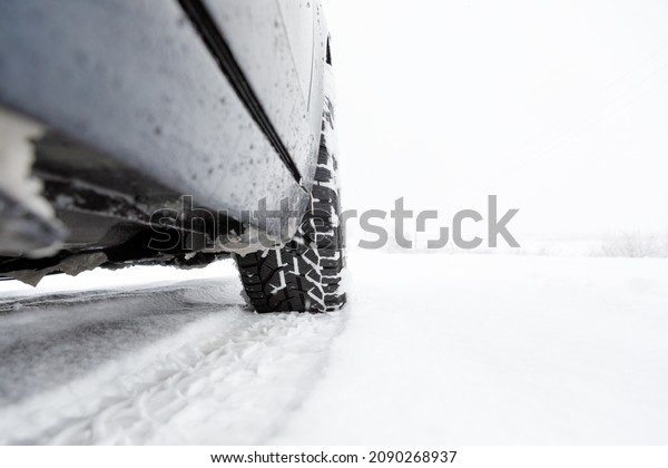 Winter tire. Car on snow road. Tires on snowy\
highway detail.