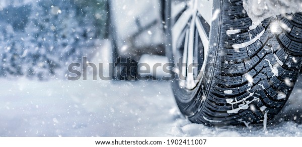 Winter tire. Detail of car tires in\
winter on the road covered with snow. Panorama,\
banner
