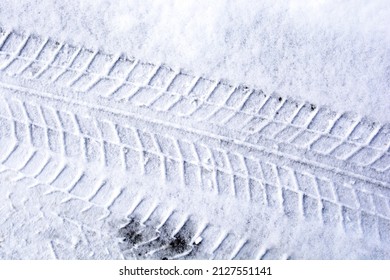 Winter tire label. Asphalt in the snow. Car tire print on frozen snowy ground.